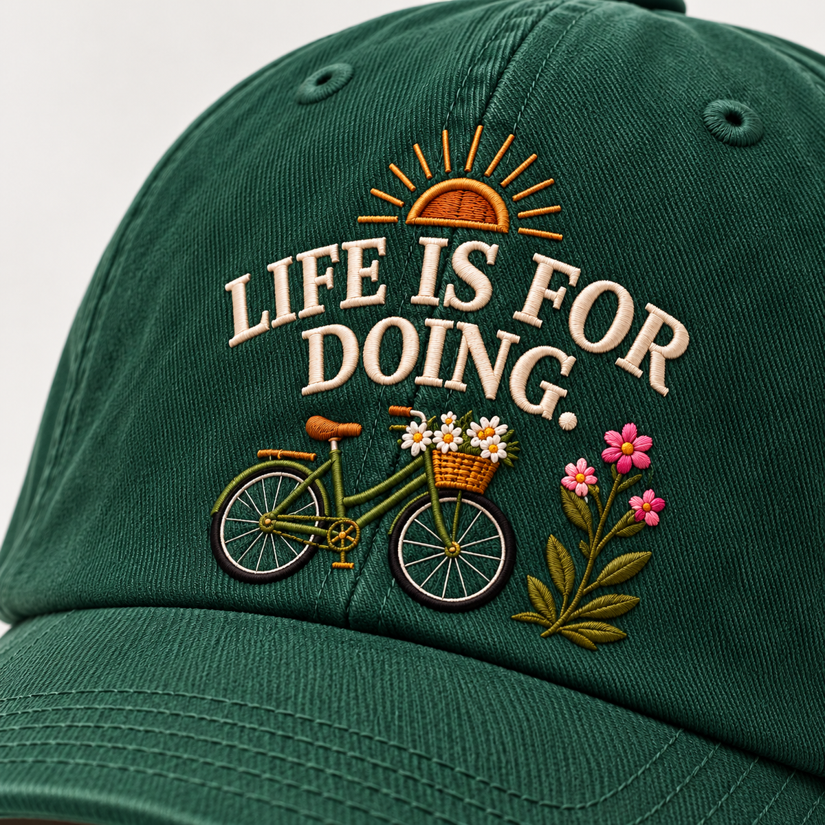 Close detail of the Life Is For Doing embroidery on the forest green cap