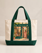 The MERRI Book Tote in cream canvas with forest green handles and the MERRI Books shopfront print